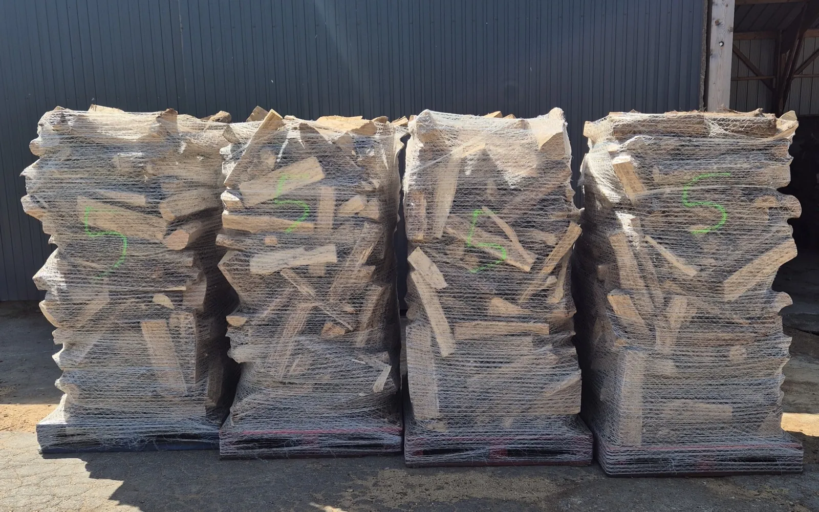 Quatre palettes de bûches de bois de chauffage, filmées et prêtes à partir